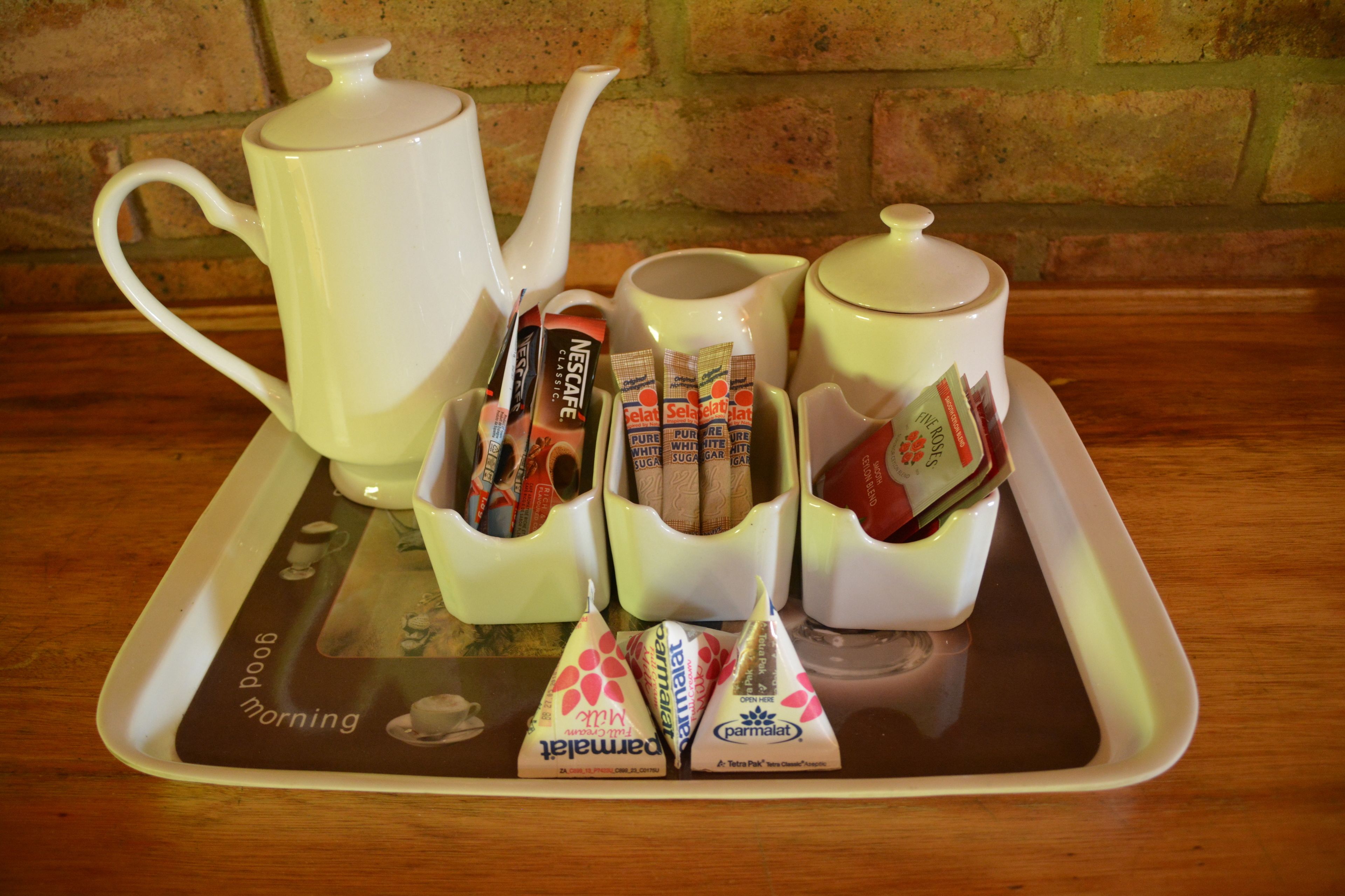 A tray with a teapot, sugar cubes, and packets of instant coffee and tea.
