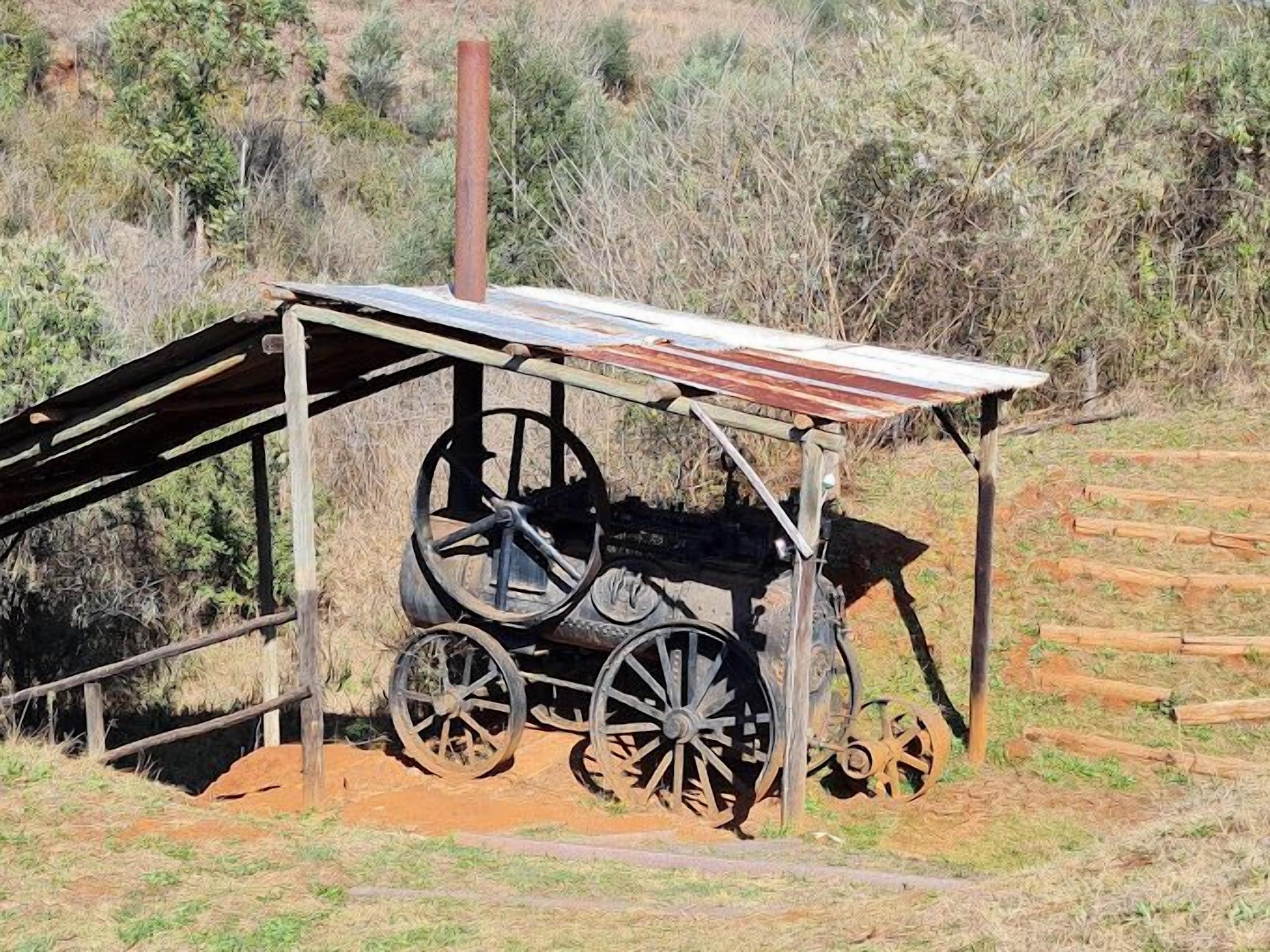 A vintage wooden cart with large spoked wheels, supported by a metal frame with a roof.