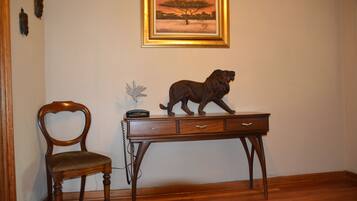 A wooden desk with a lion statue, a chair, and a framed picture on the wall.
