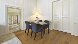 Ett matområde med ett bord, stolar och en lampa. Det finns två dörrar och en hall som leder till ett annat rum.