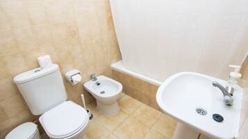 Un bagno con il water, un bidet, un lavandino e un cestino.