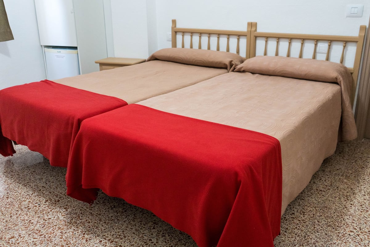 Una cama doble con dos colchas rojas y un cabecero de madera.