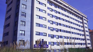 Un hôtel à plusieurs étages, doté d’un design moderne, avec une série de balcons et une enseigne bien visible au niveau du rez-de-chaussée.