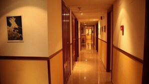 Un couloir d’hôtel avec des portes en bois, un plancher ciré et des œuvres d’art encadrées accrochées aux murs.