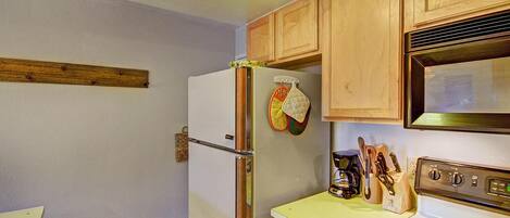 A kitchen with wooden cabinets, a refrigerator, a stove, and a microwave.