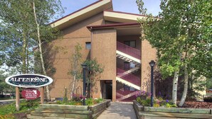 Un edificio de dos pisos con techo rojo, un balcón y una escalera.