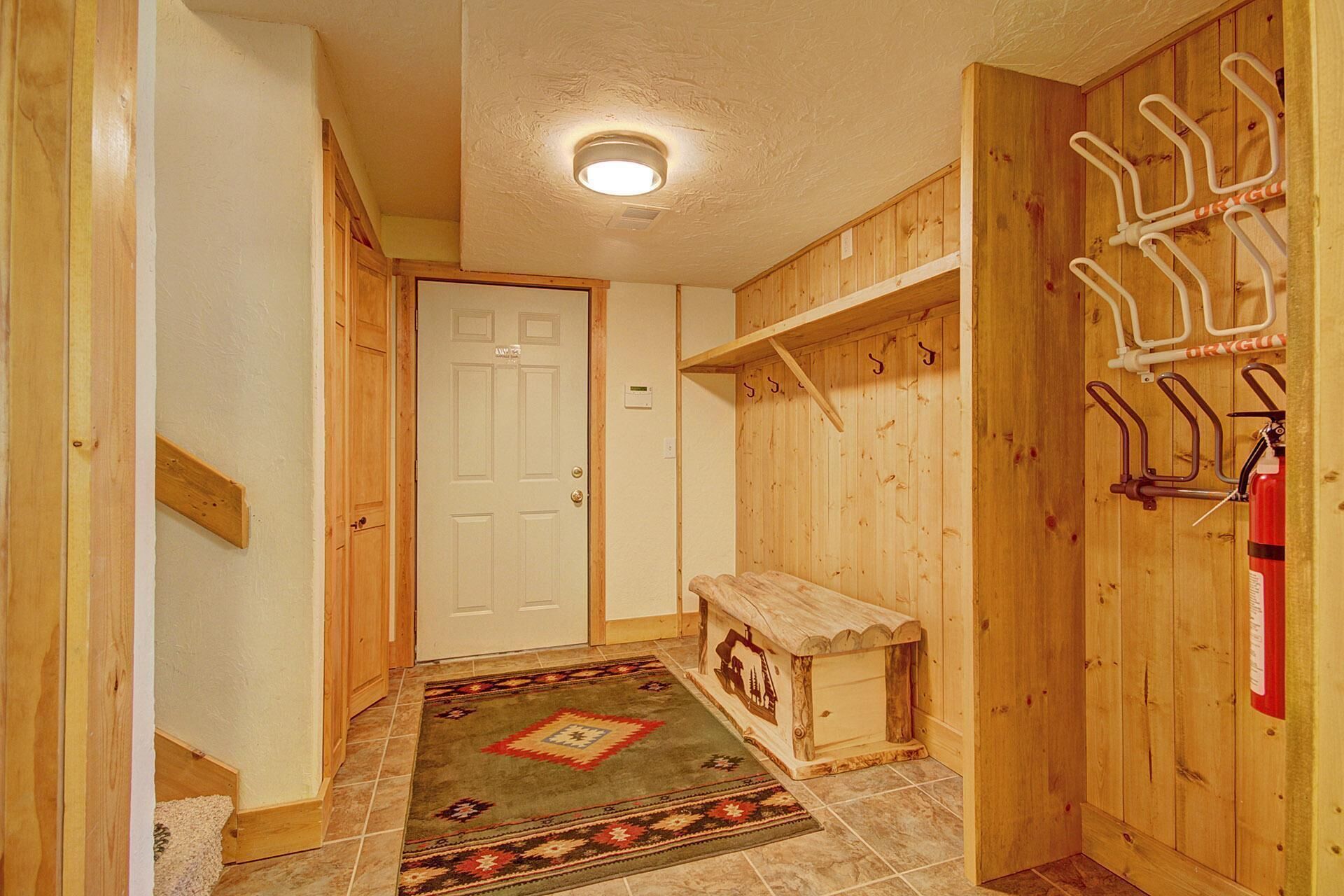 A hallway with a wooden door, a bench, and a coat rack.