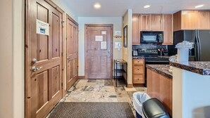 A compact kitchen with wooden cabinets, a microwave, and a refrigerator. - Highland Greens Lodge 210 1 Bedroom Condo by RedAwning (Breckenridge)