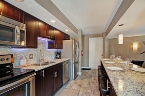 Una cocina moderna con armarios de madera oscura, electrodomésticos de acero inoxidable y encimera de mármol.