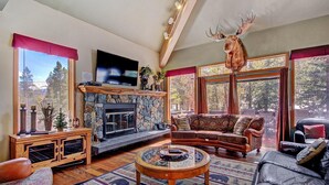 A cozy living room with a stone fireplace, leather sofas, and a mounted moose head.