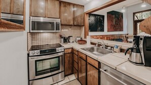 A modern kitchen with wooden cabinets, stainless steel appliances, and a tiled backsplash. - 57sw - Fireplace - Wifi -  Sleeps 6 2 Bedroom Home by RedAwning (Deming)