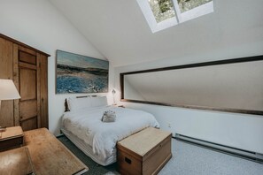 A bedroom with a bed, a wooden cabinet, a desk, a lamp, a painting, and a skylight. - 57sw - Fireplace - Wifi -  Sleeps 6 2 Bedroom Home by RedAwning (Deming)