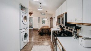 Een compacte keuken met een wasmachine, een eethoek met een houten tafel en een moderne kookplaat.