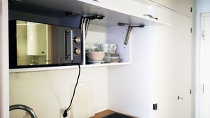 Une cuisine de taille réduite, équipée d’un évier, d’une cuisinière et d’un plan de travail.
