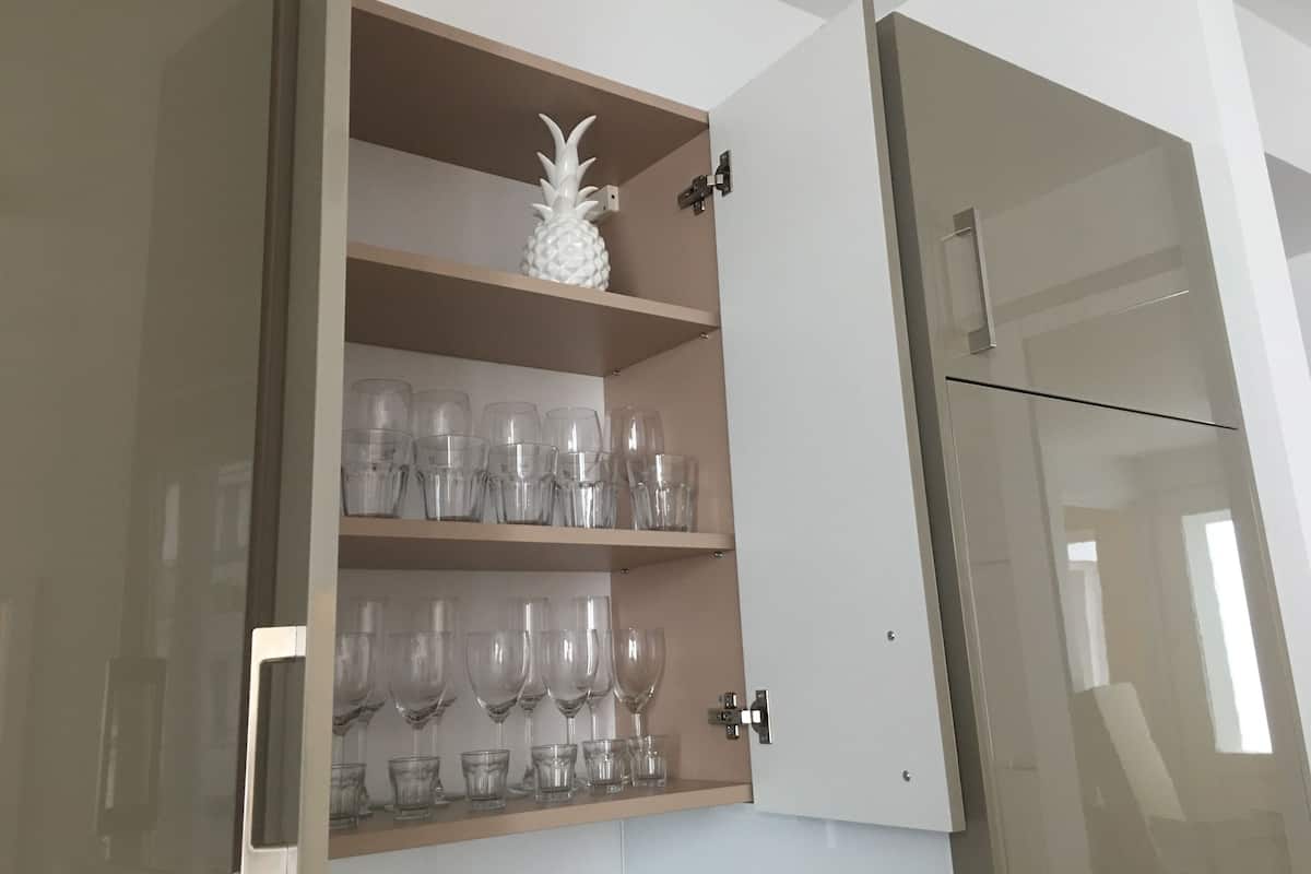 Una cocina con un mueble empotrado que contiene cristalería y una decoración de piña.
