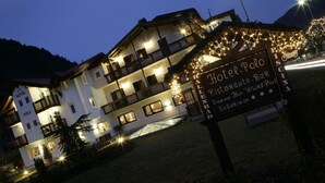 Un hôtel doté de nombreux balcons, d’un panneau indiquant les équipements disponibles et d’une entrée bien éclairée.