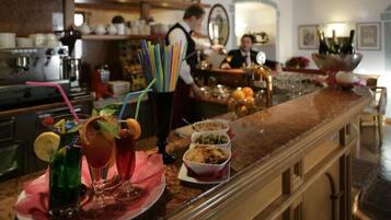 Eine Bar mit einer Auswahl an Getränken und Snacks, darunter farbenfrohe Cocktails und kleine Schalen mit Speisen.