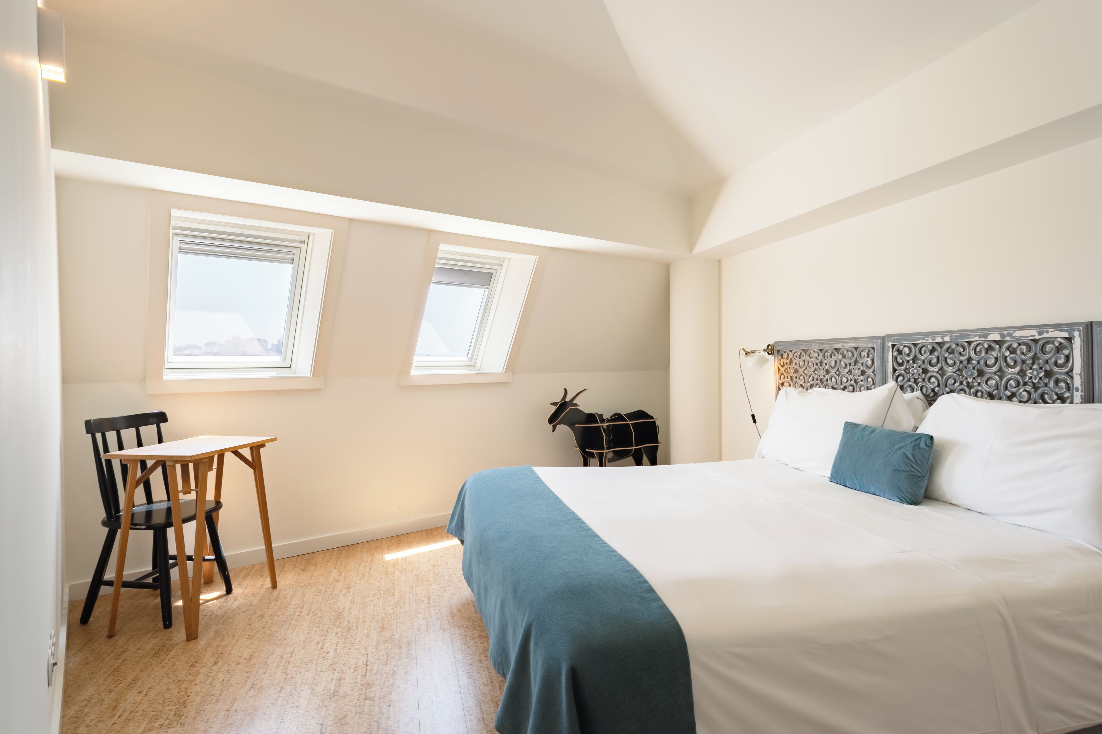 A bedroom with a bed, a desk, two windows, and a decorative headboard.