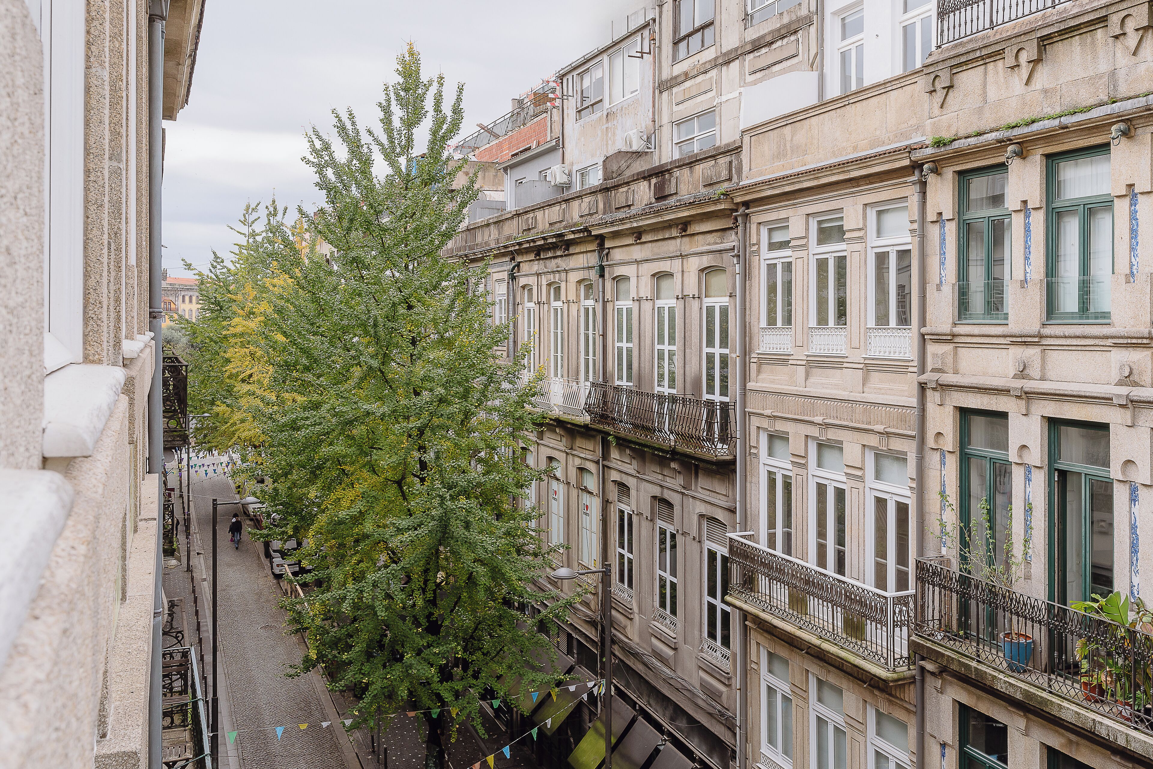Une rue étroite, bordée de bâtiments des deux côtés, avec des balcons dotés de rampes et de fenêtres.