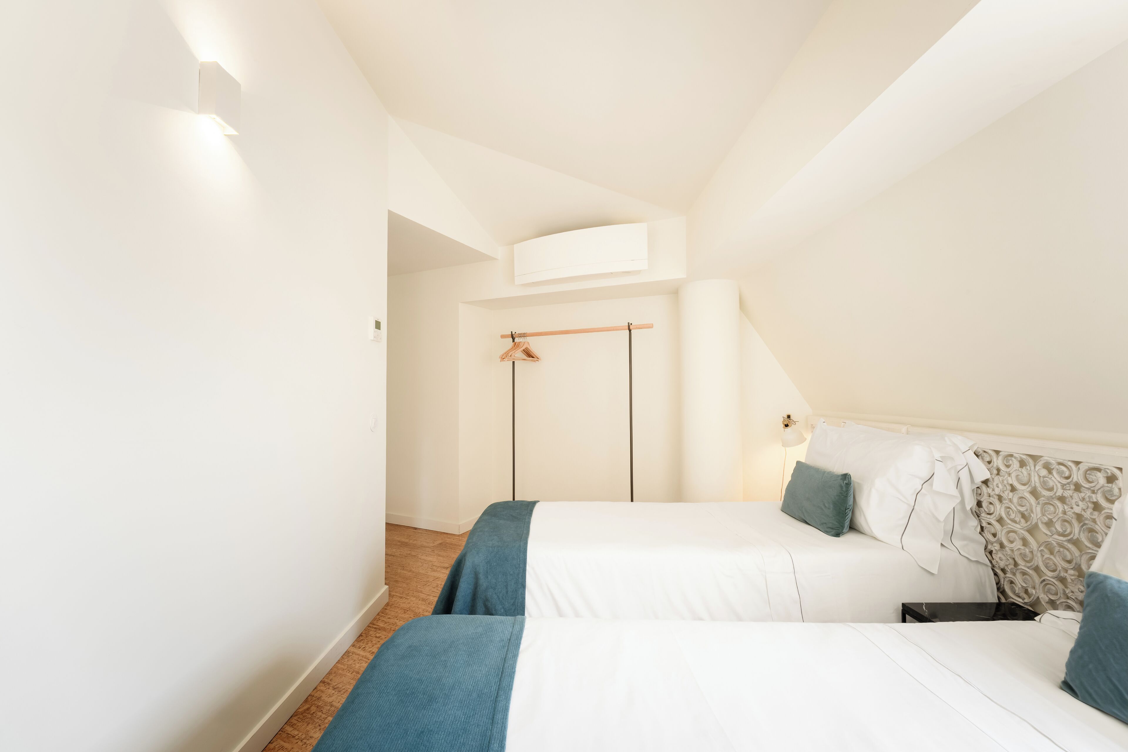 A bedroom with two beds, a wardrobe, and a ceiling light.