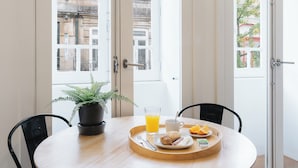 A breakfast tray with croissants, orange juice, and a plant on a table by a window. - Galerias Nightlife Fashion Flats by Feel Porto (Porto)