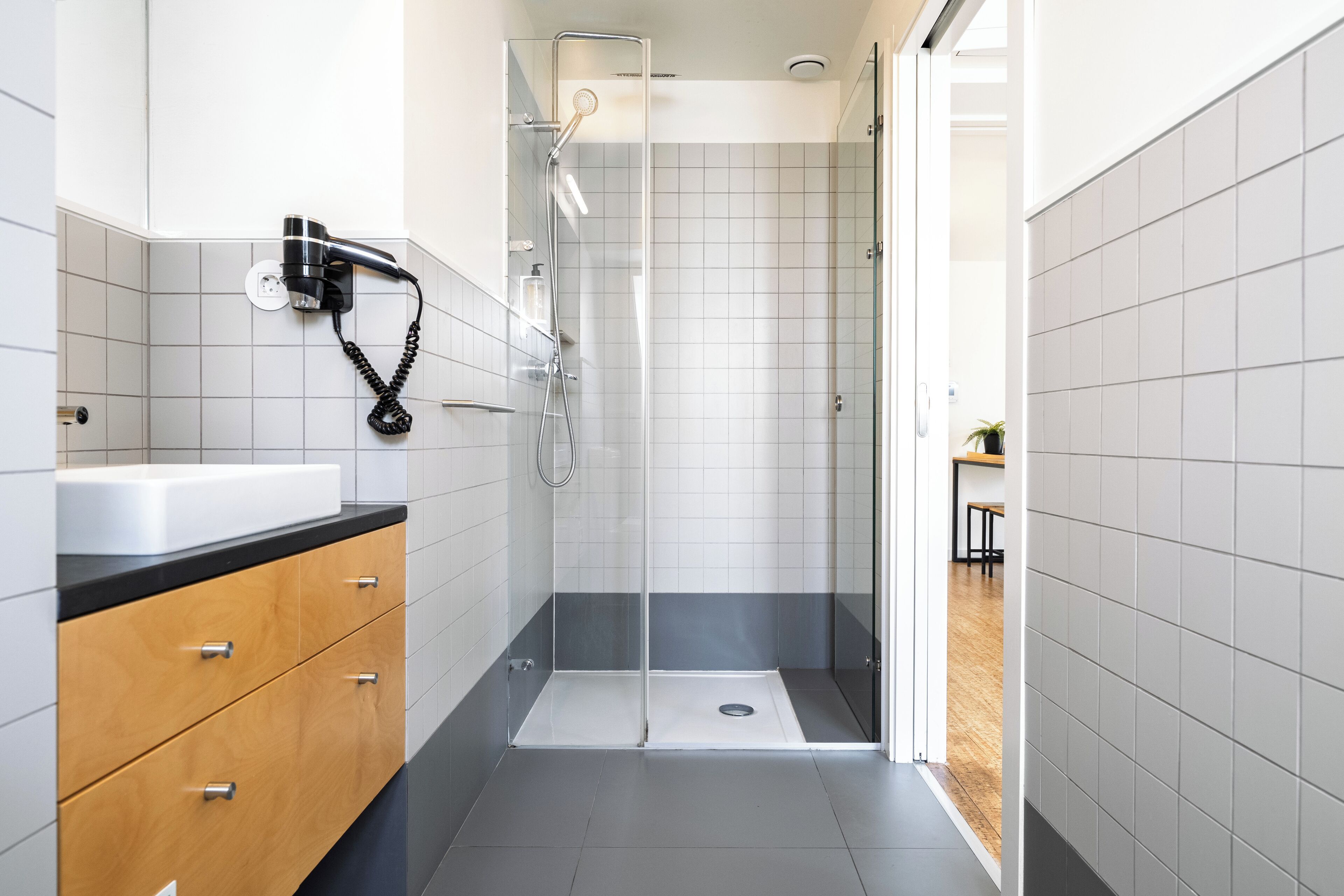 A modern bathroom with a shower, a sink, and wooden cabinets.