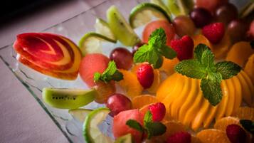 Una placa de vidrio con diversas frutas cortadas y hojas de menta.