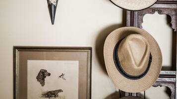 A wall with a framed wildlife illustration, a wall-mounted light fixture, and several hats arranged vertically.