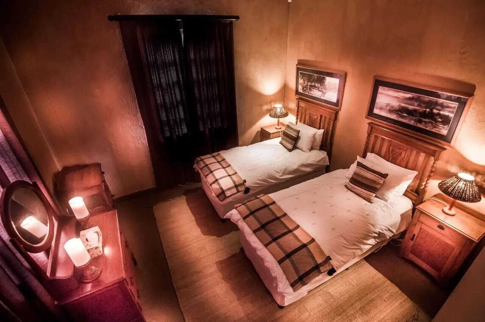A hotel room with two beds, a mirror, a nightstand with a lamp, and a picture on the wall.