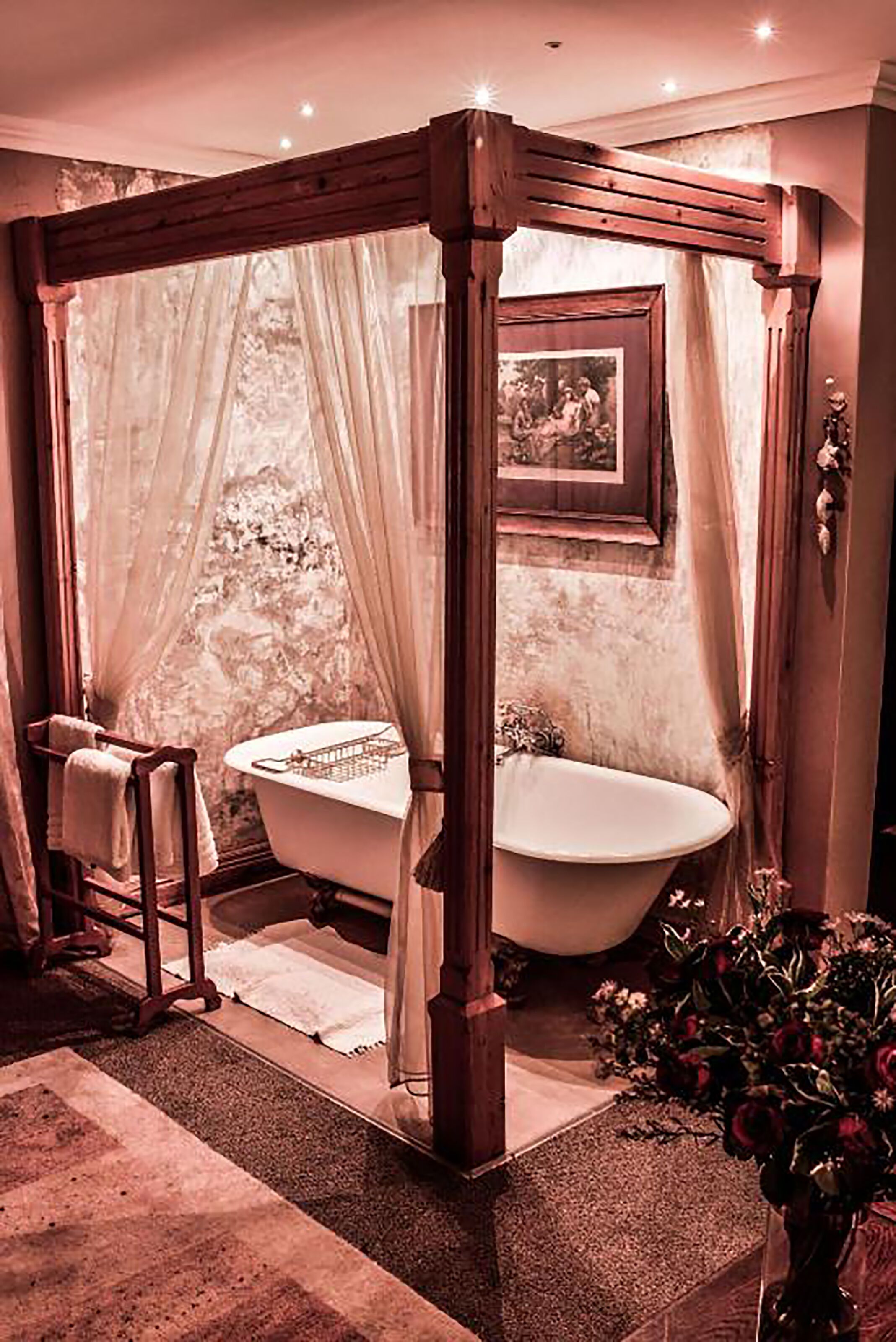 A bathroom with a freestanding bathtub, a wooden canopy, and a framed picture on the wall.