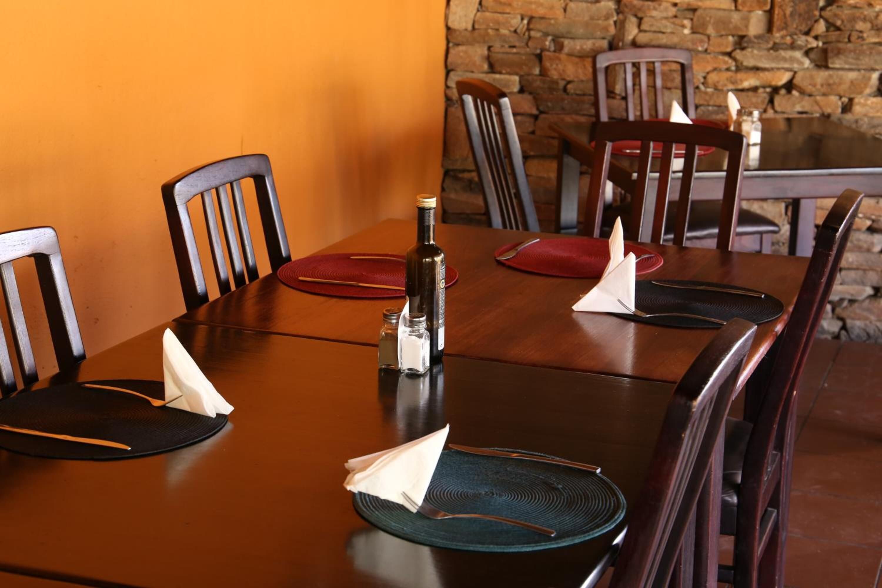 A dining table set with placemats, napkins, and a bottle.