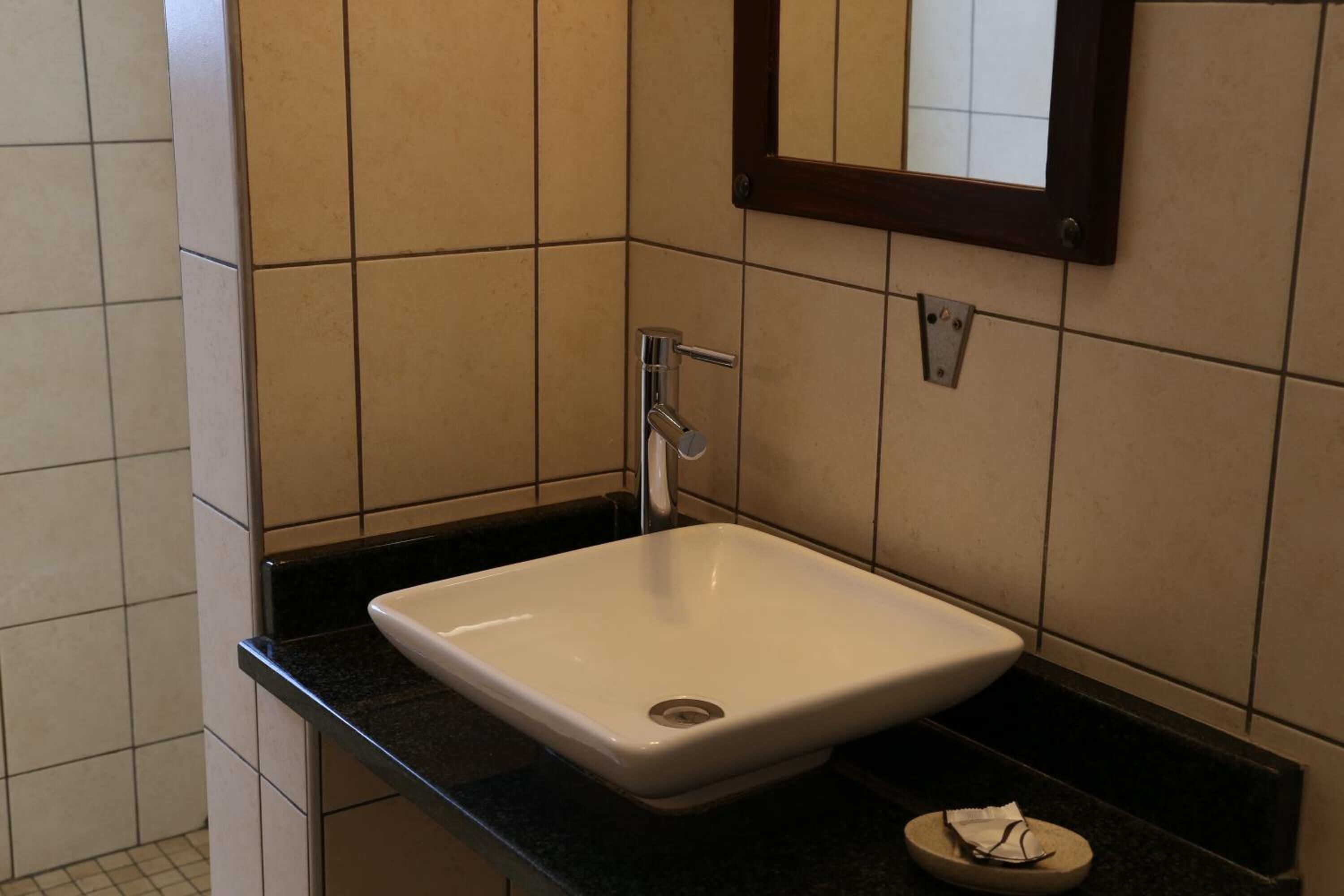 A bathroom with a white sink, black countertop, and a mirror above the sink.