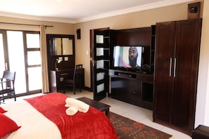 Una habitación de hotel con cama, escritorio, televisor y armario.