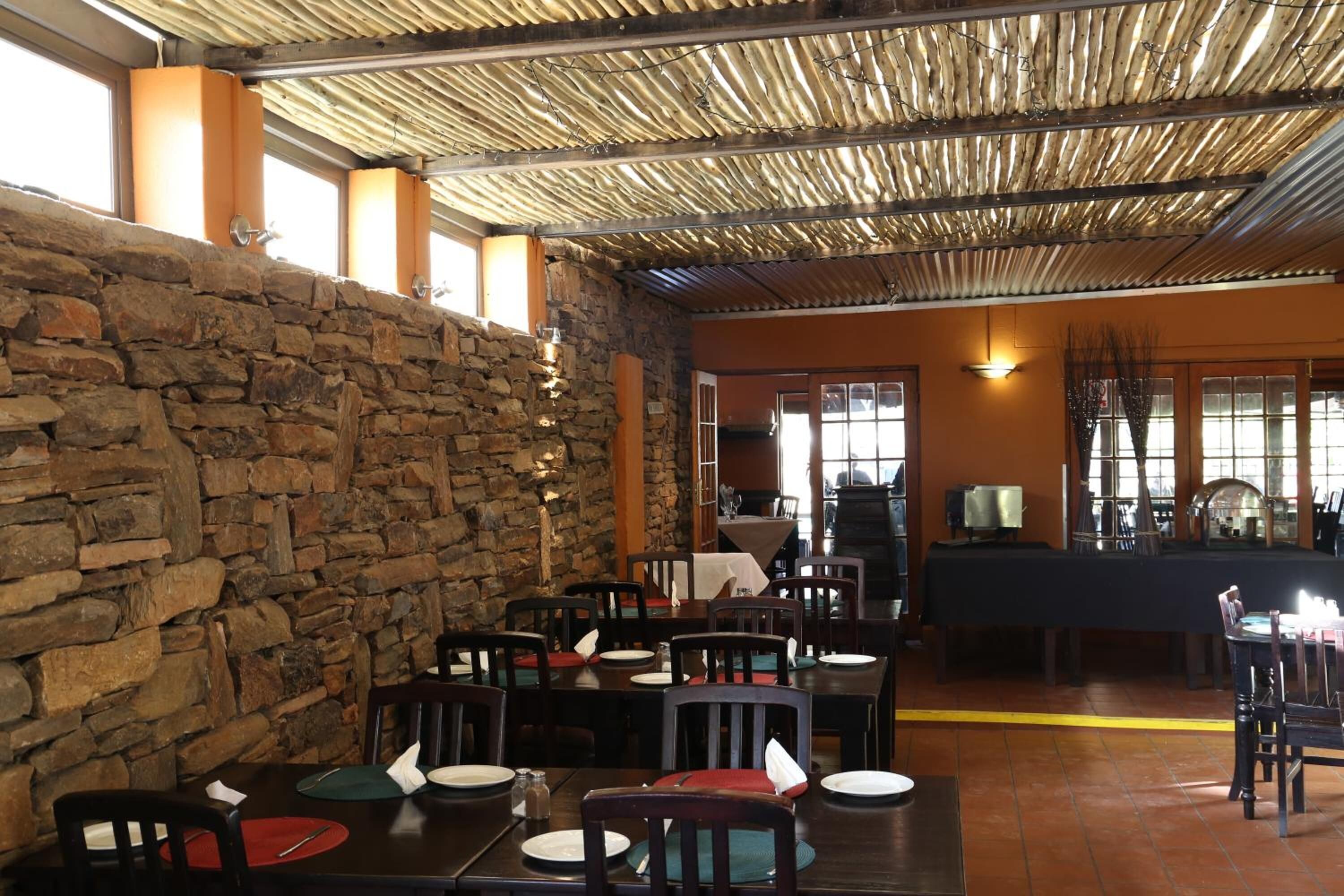 A restaurant with stone walls, wooden tables, and chairs.