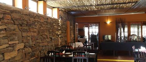 A restaurant with stone walls, wooden tables, and chairs.