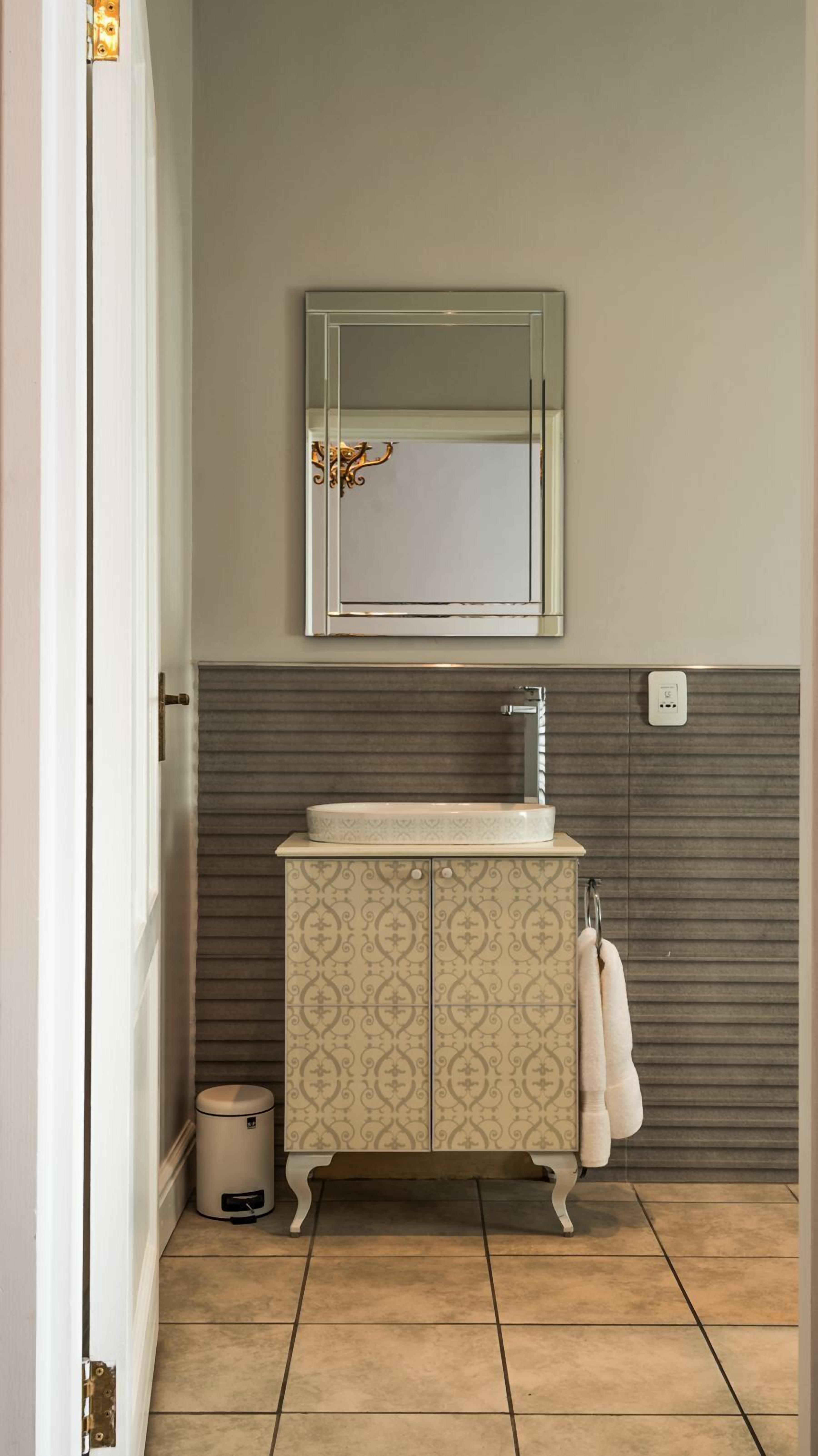 A bathroom with a white vanity, a mirror above it, and a towel hanging on the wall.