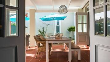 A dining area with a table and chairs, a hanging light fixture, and a view of the outside.