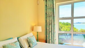 A hotel room with a large bed, a lamp, and a view of the sea. - Gold Water (Cape Town)