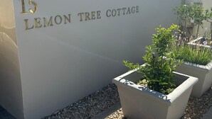 A building with a sign reading "15 LEMON TREE COTTAGE" and potted plants in front. - Lemon Tree Cottage (Franschhoek)