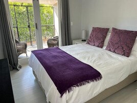 Une chambre à coucher avec un lit, un plaid violet et deux coussins assortis.