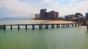 A pier extending into a body of water with a cityscape in the background. - Topaz (Cape Town)
