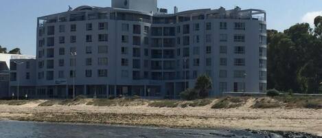 A multi-story hotel with a modern architectural design, featuring balconies and a beachfront location.