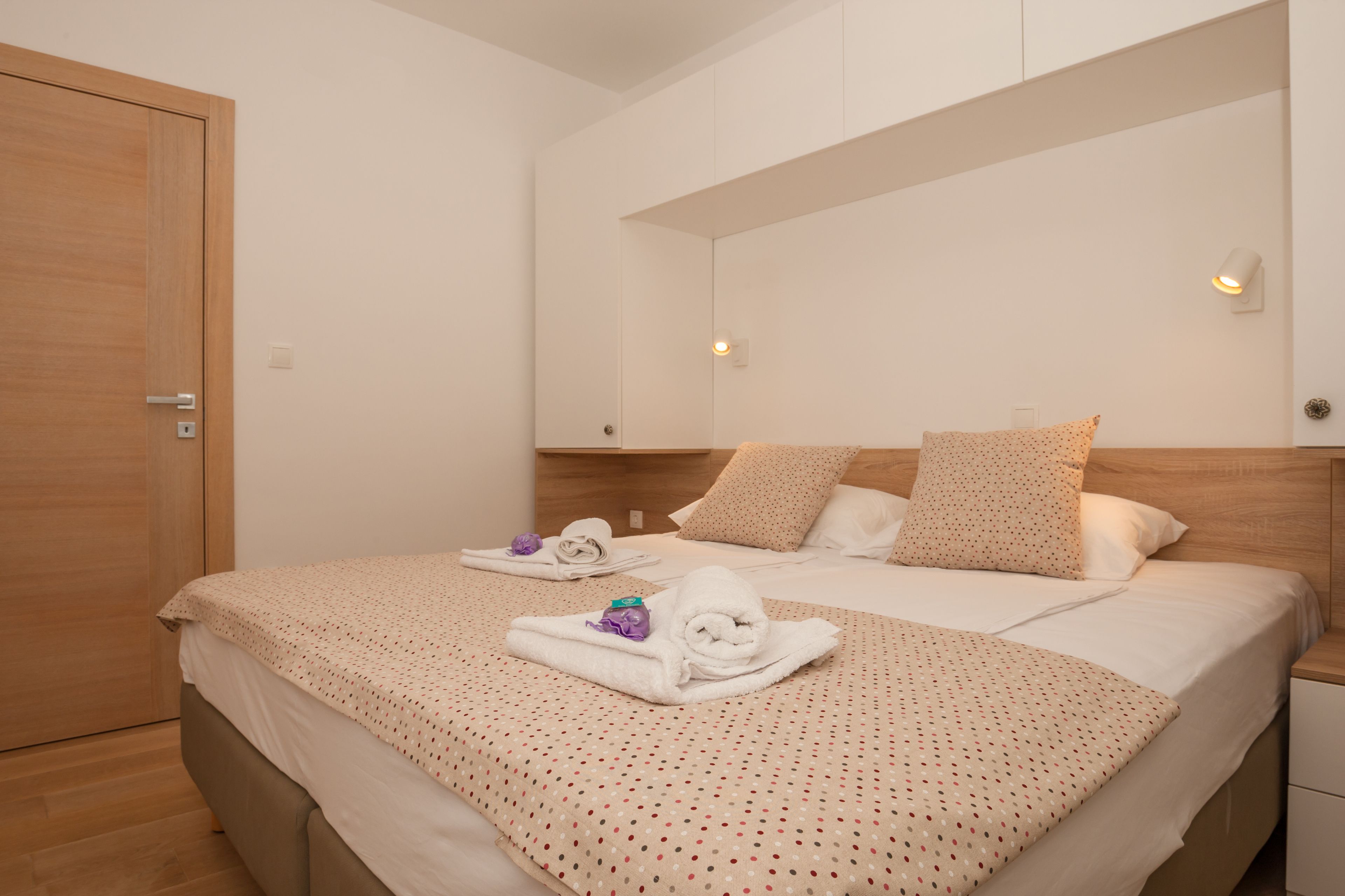 A hotel room with a large bed, a wooden wardrobe, and a mirror on the wall.