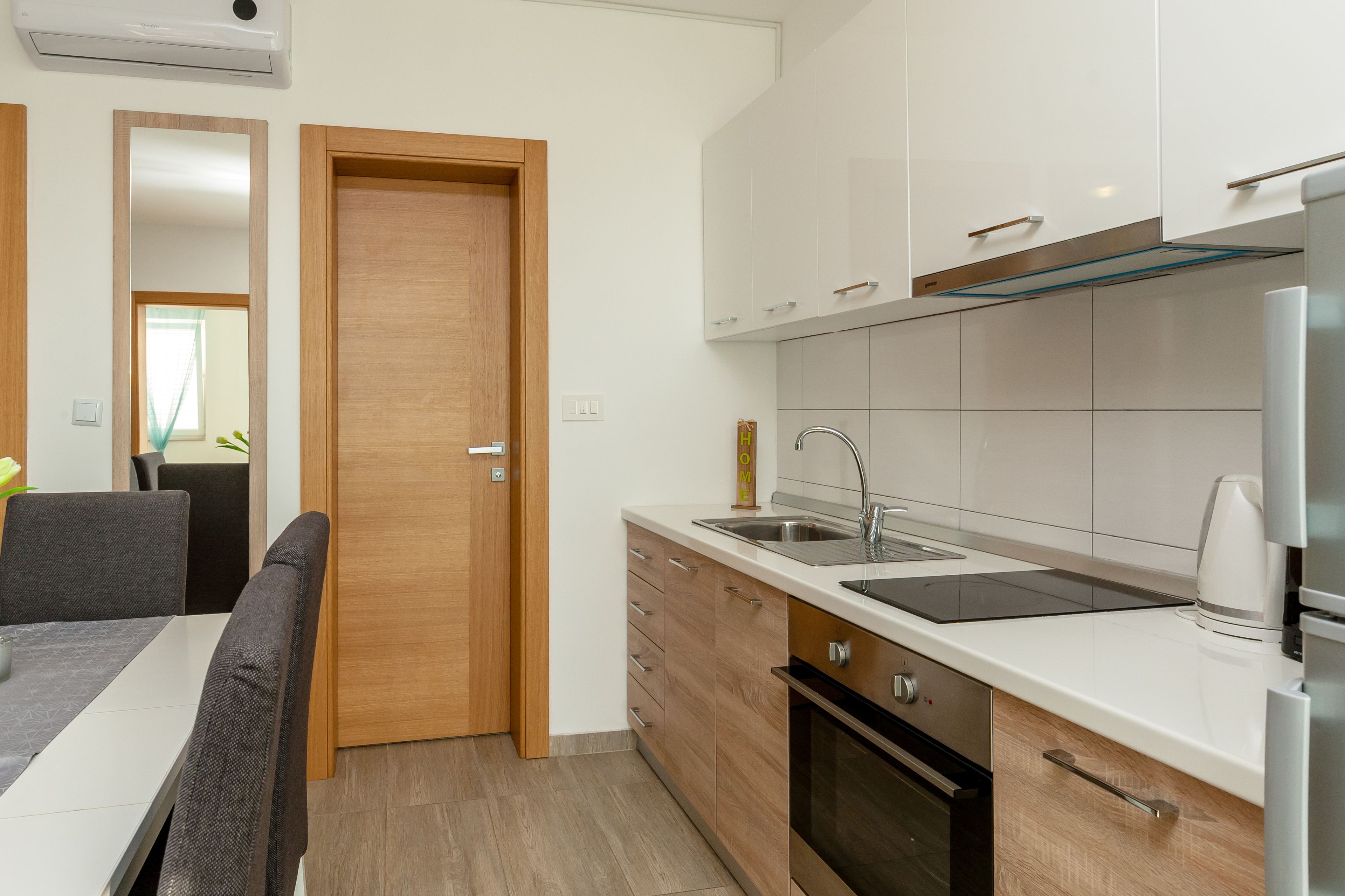 A modern kitchen with white cabinets, a stainless steel sink, and a built-in oven.