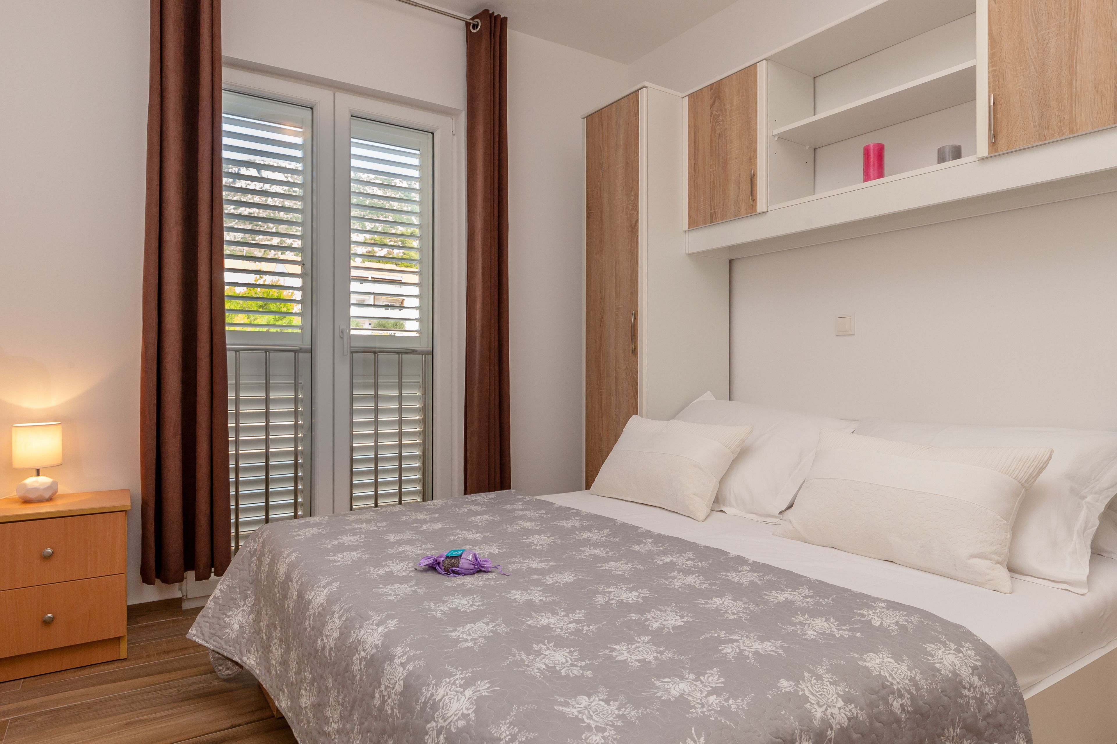 Ein Schlafzimmer mit Bett, Nachttisch, Kleiderschrank und einem Fenster mit Jalousien.