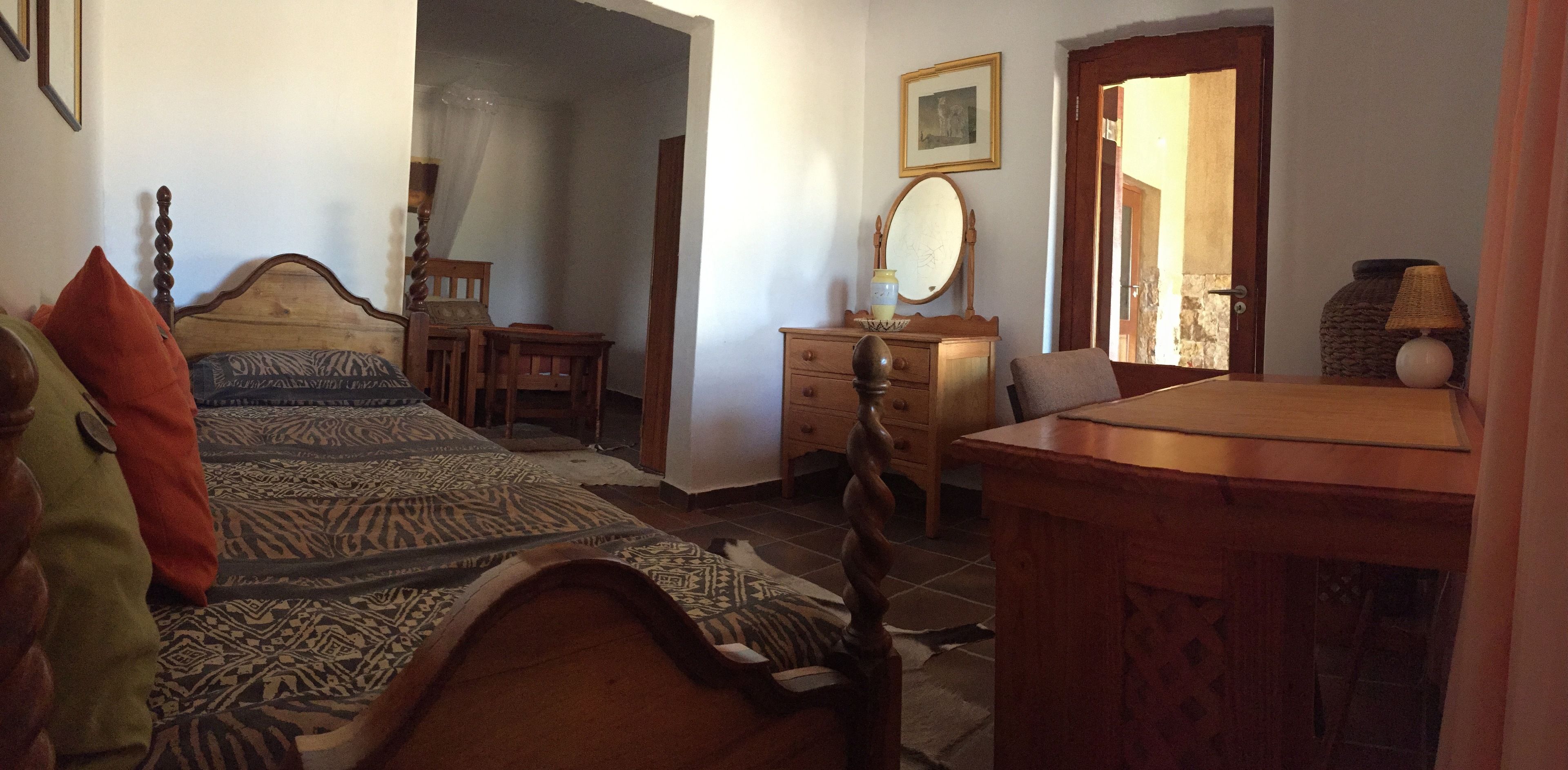 A bedroom with a bed, a dresser, a chair, a desk, and a mirror.