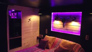 A bedroom with a bed, pillows, a wall-mounted skull decoration, and a shelf with a small item.
