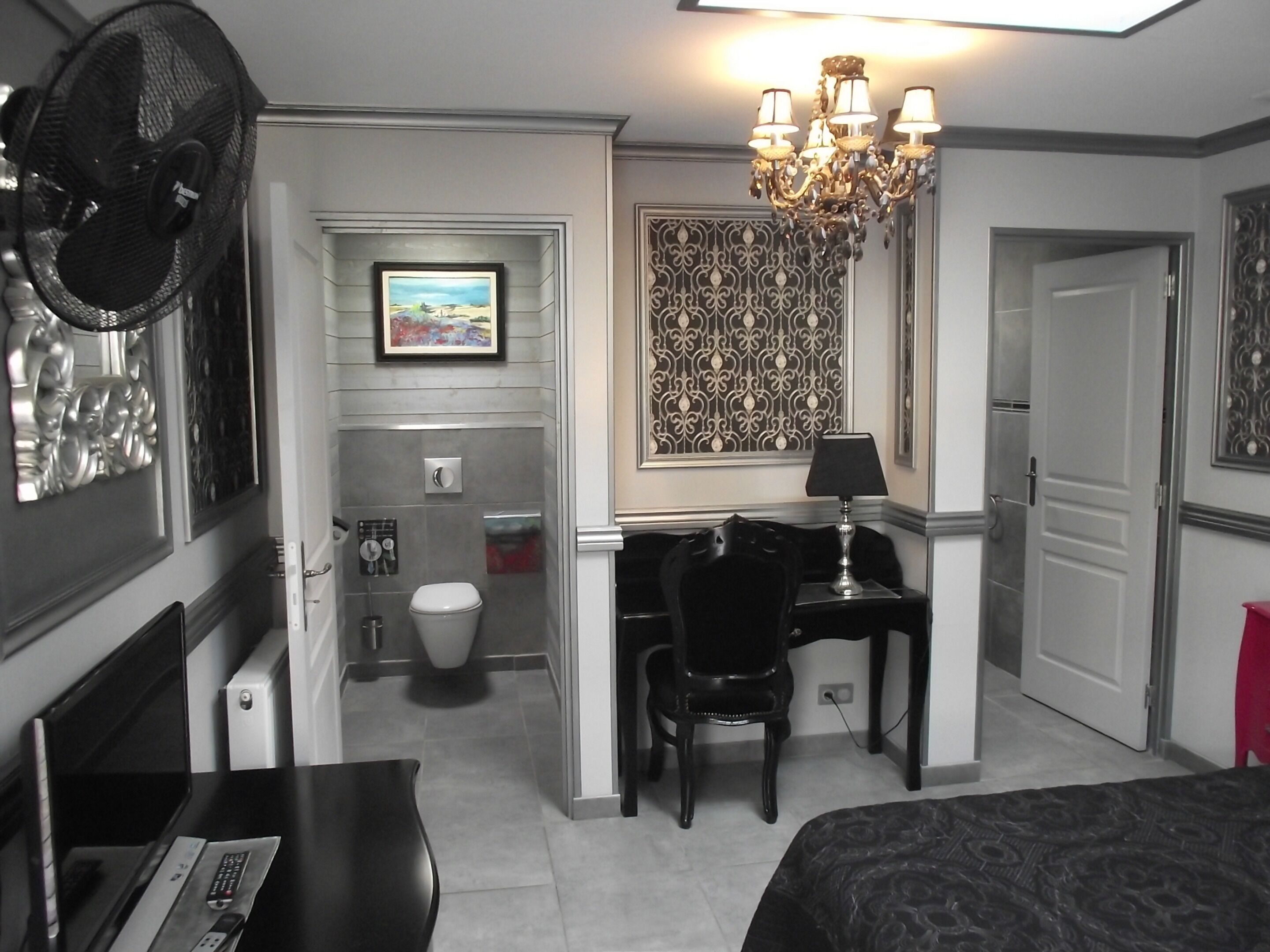 Habitación de hotel con escritorio, silla, cama y baño con inodoro y ducha.
