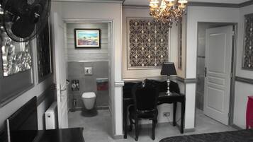 Habitación de hotel con escritorio, silla, cama y baño con inodoro y ducha.