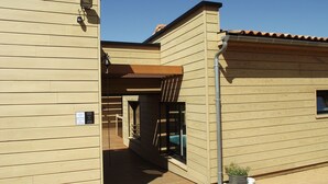 Ein Gebäude mit Holzfassade, einem überdachten Eingang und einem kleinen Fenster.